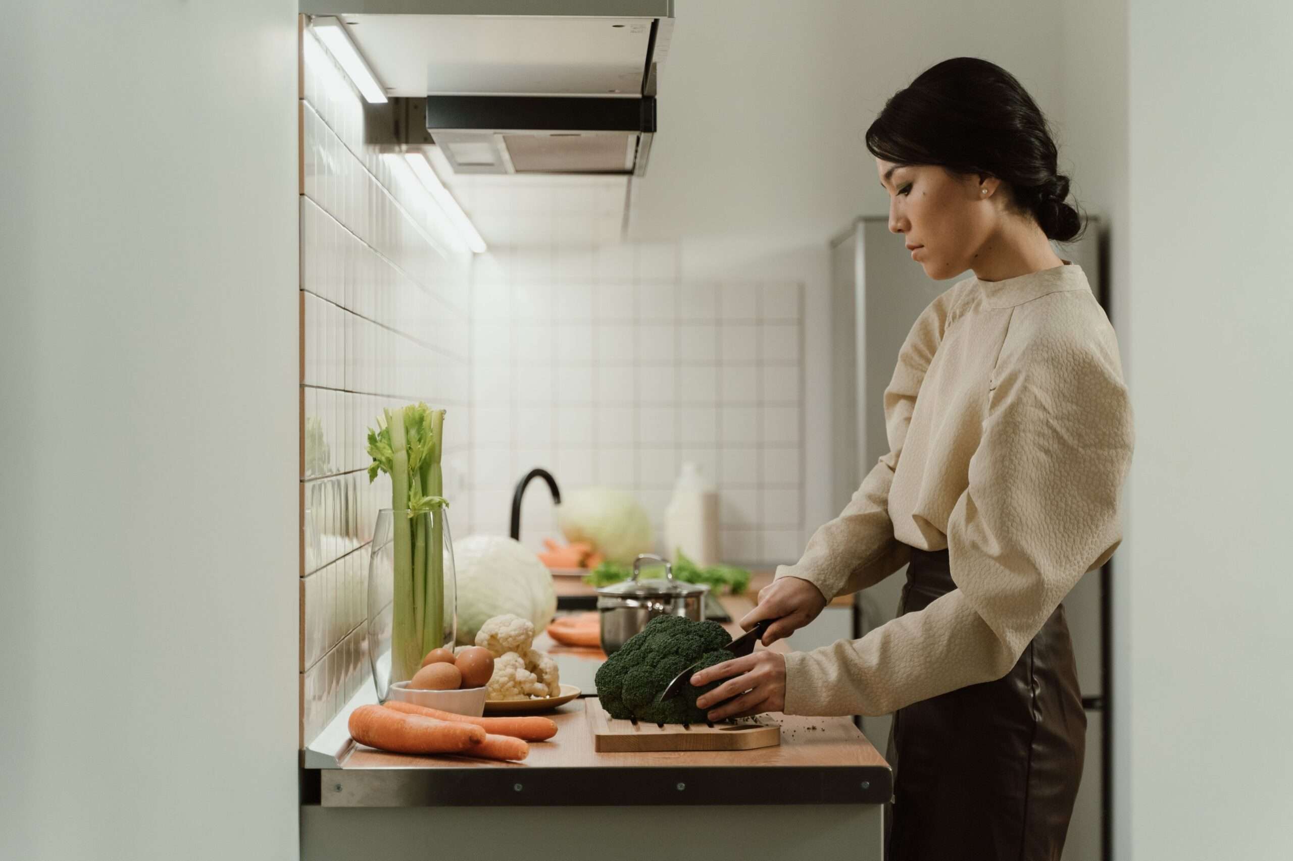 Hands slicing fresh broccoli, a cruciferous vegetable on Dr. Gundry's yes foods list