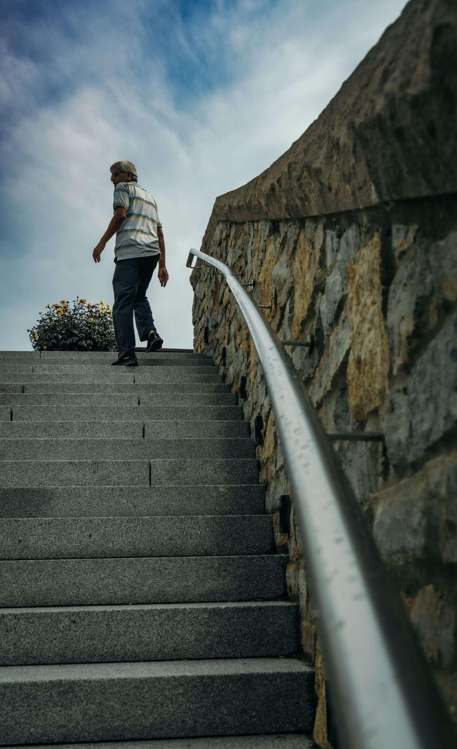 Older man climbing outdoor stone stairs, a simple weight-bearing exercise for bone density