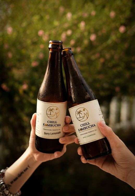 Two people toasting with kombucha bottles, one of the best fermented foods for gut health