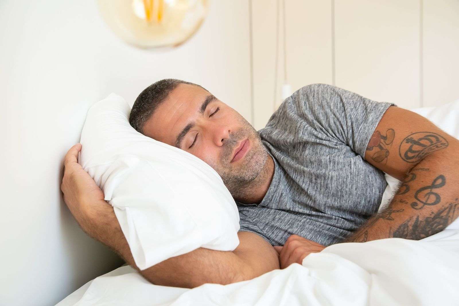 Man sleeping on his side with a supportive pillow, the best sleeping position for snoring and reflux