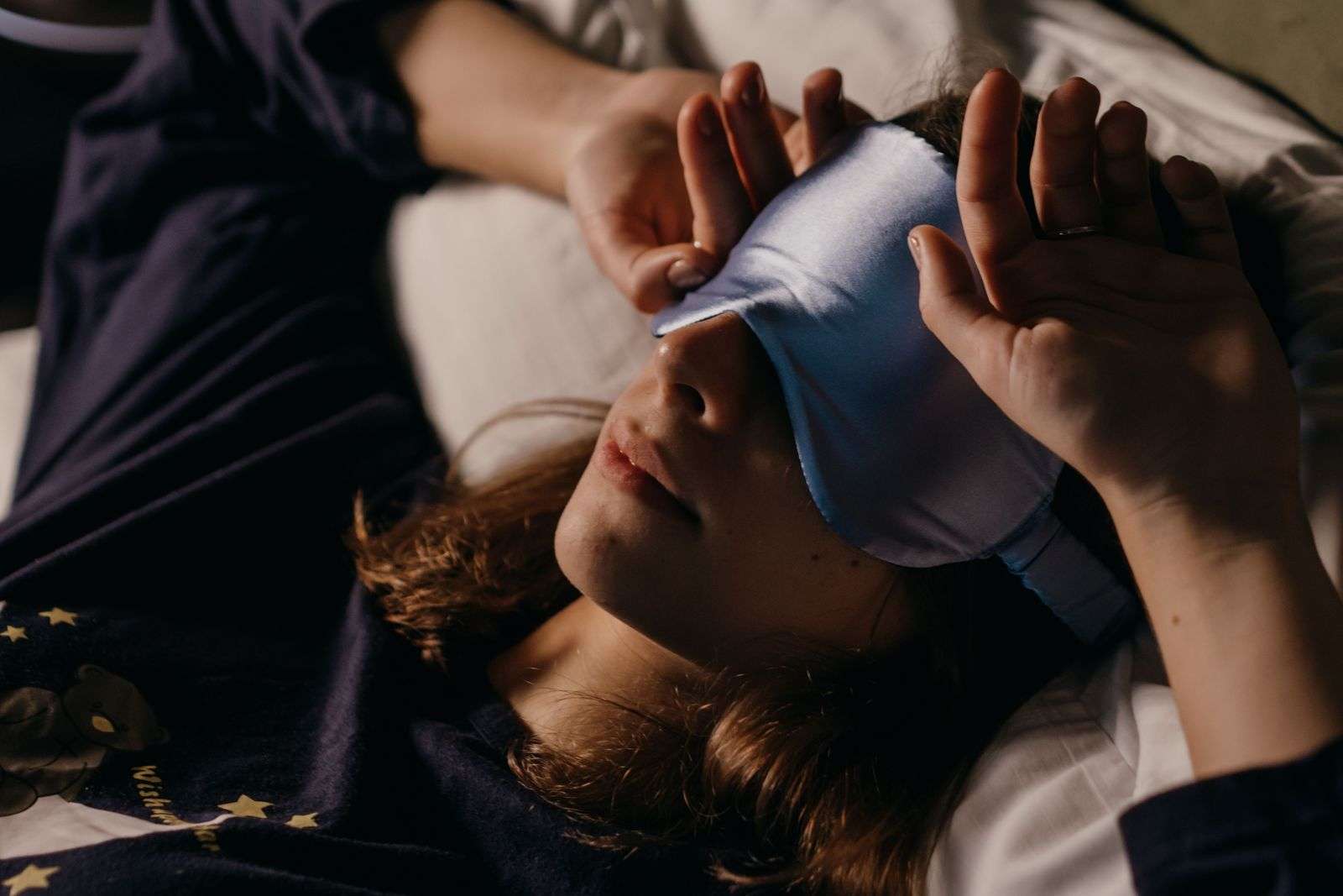 Woman wearing a silk sleep mask for better sleep quality, part of the author's sleep routine
