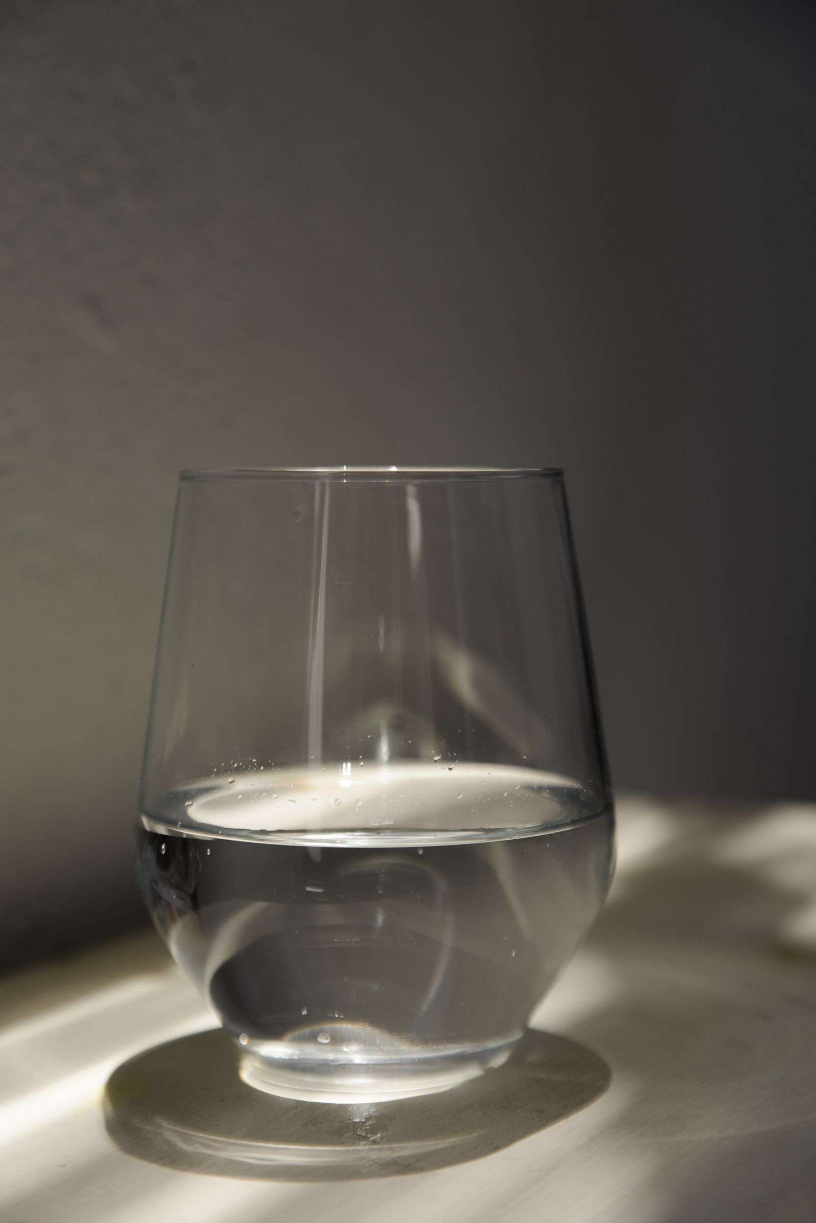 Glass of water on a sunlit table, the hydrated alternative to dry fasting