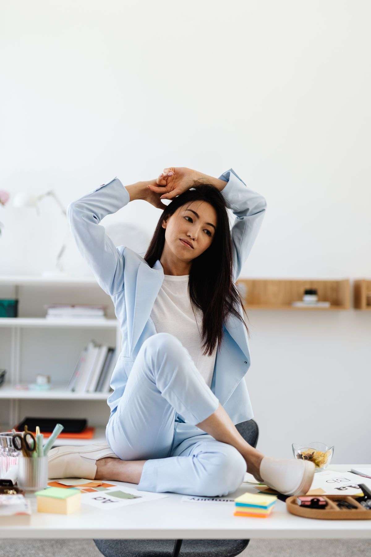 Woman stretching her neck and shoulders at her desk, one of the exercises for people who sit all day