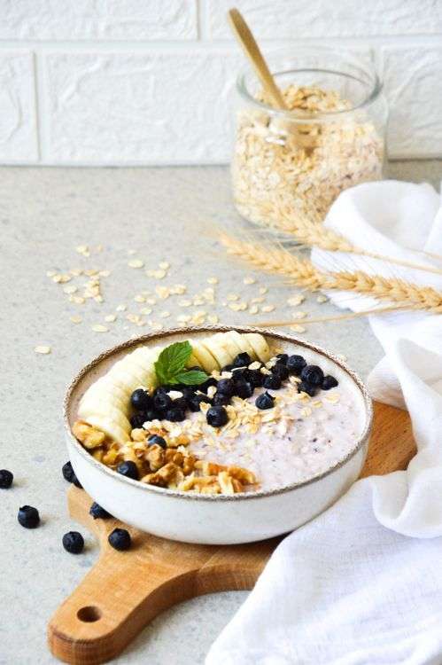 Oatmeal bowl with blueberries and banana, one of the foods that lower cholesterol fast thanks to soluble fiber beta-glucan.