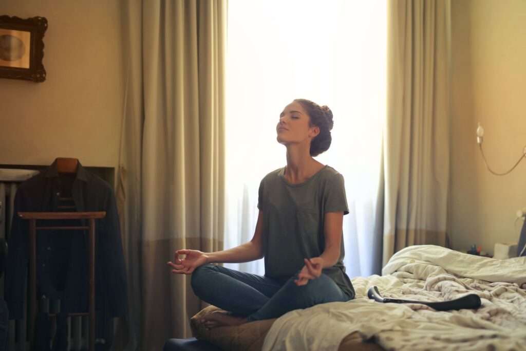 Woman meditating in a calm bedroom, a mindfulness practice that supports the gut-brain axis