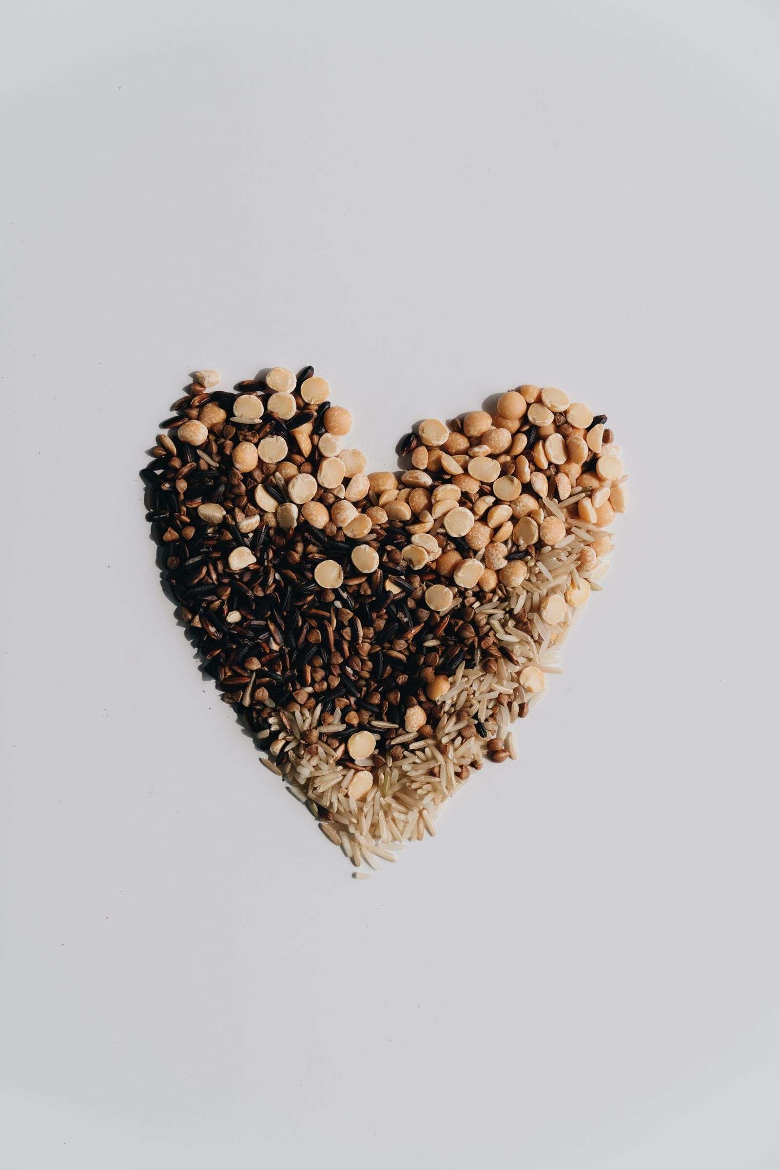 Heart shape made of whole grains and legumes on a white background, illustrating heart healthy foods that help lower blood pressure naturally