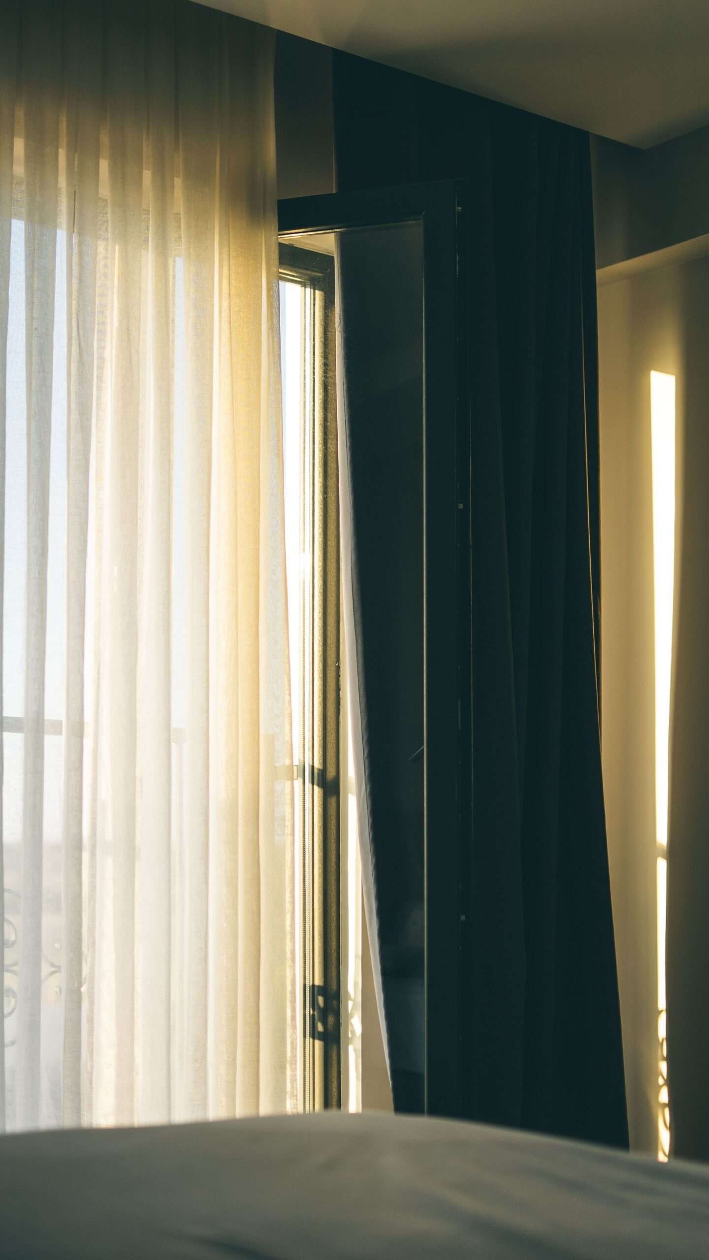 Warm morning sunlight streaming through sheer bedroom curtains, the first step to improve sleep quality naturally.
