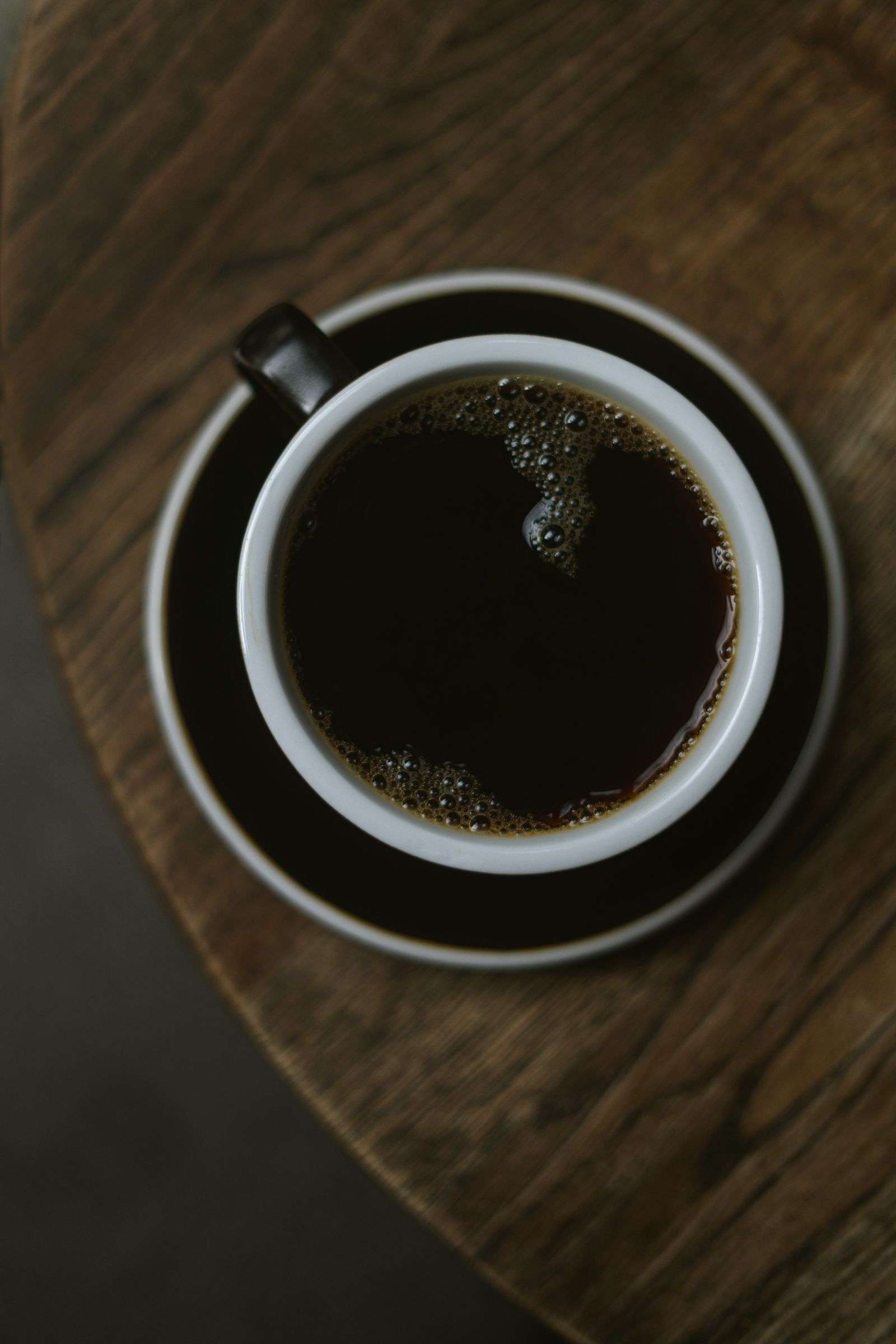 Steaming cup of black coffee in a black cup, a zero-calorie drink allowed during intermittent fasting for beginners