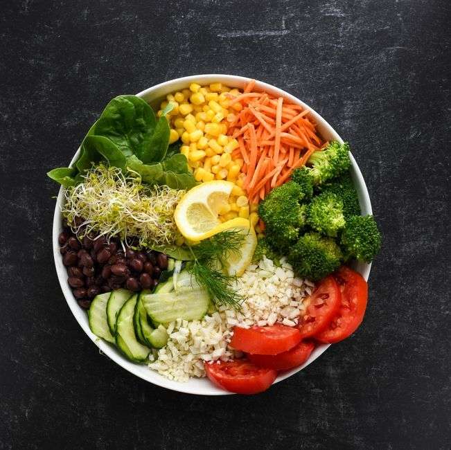 Colorful vegetable bowl with black beans, corn, carrots, broccoli and tomatoes, a healthy meal for breaking a fast during intermittent fasting for women