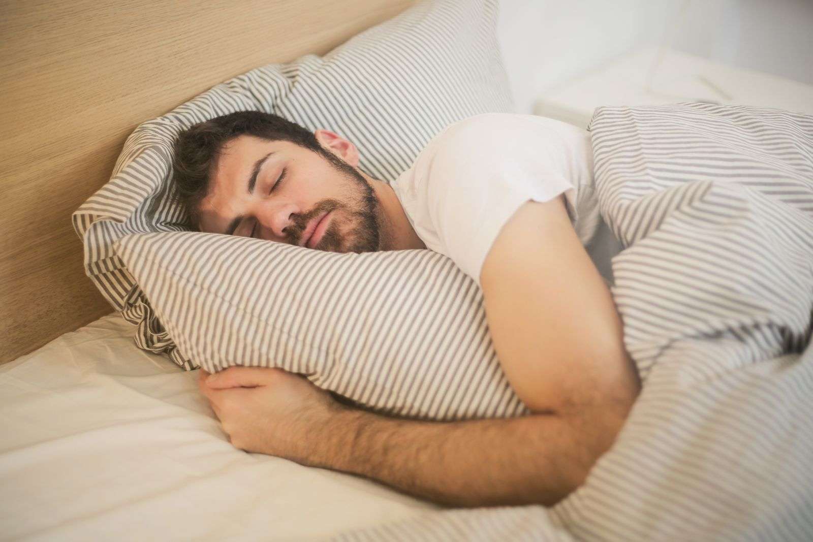 Man sleeping peacefully in bed with striped bedding