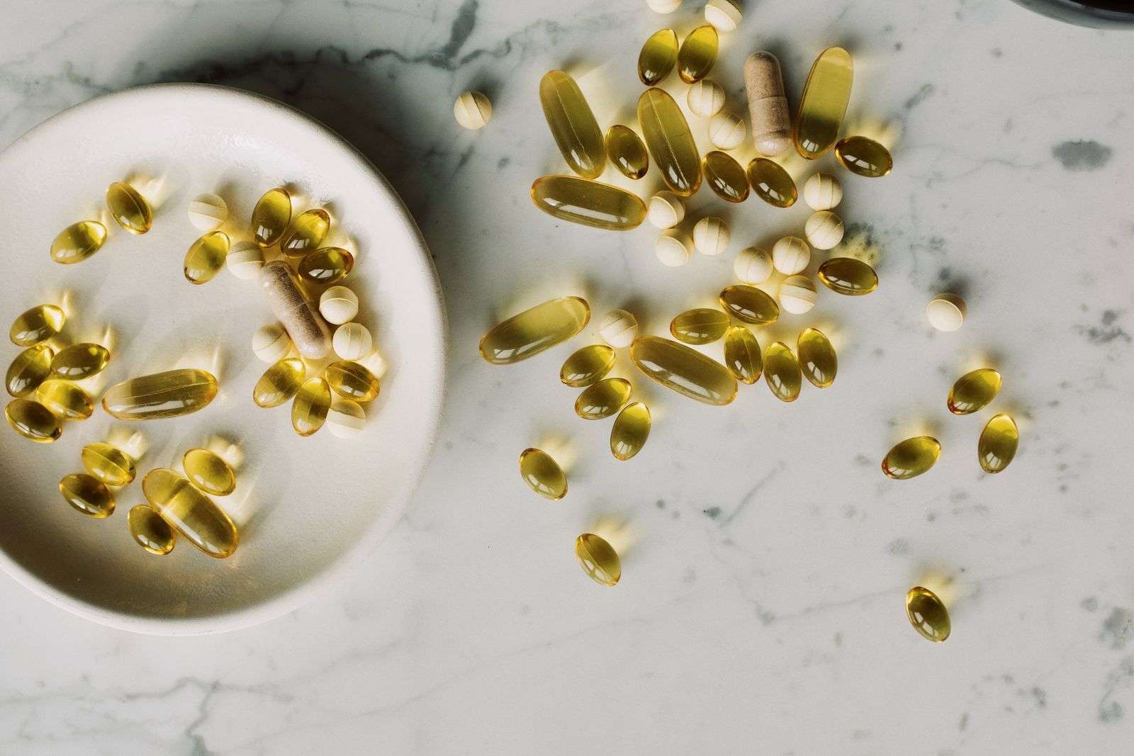 Assorted supplement capsules and pills on a marble surface