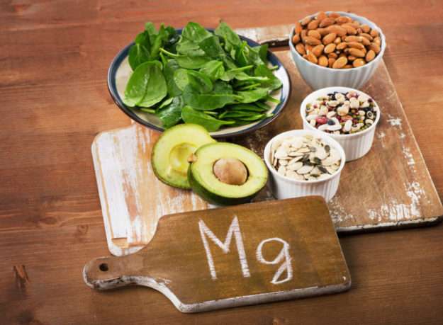 Magnesium-rich foods including bananas, almonds, spinach, and dark chocolate on a table