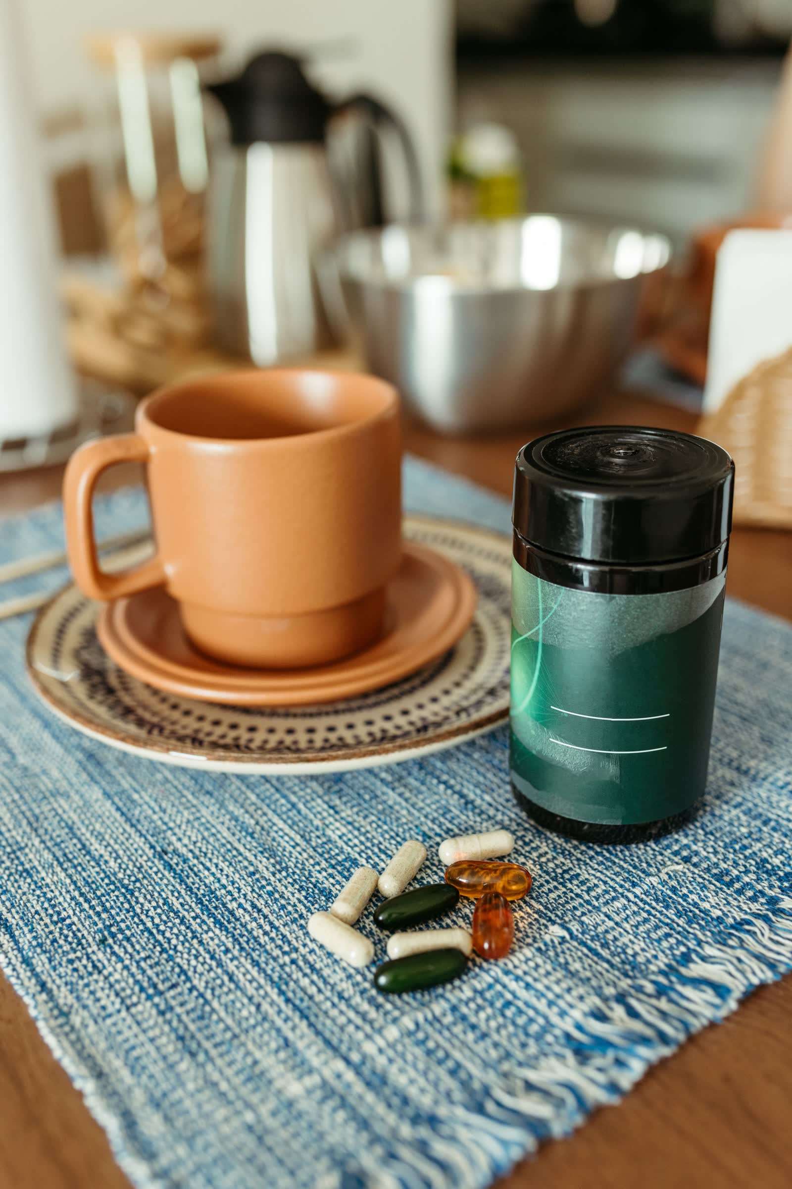 Supplement capsules and a cup on a table at bedtime, part of the melatonin vs magnesium for sleep comparison