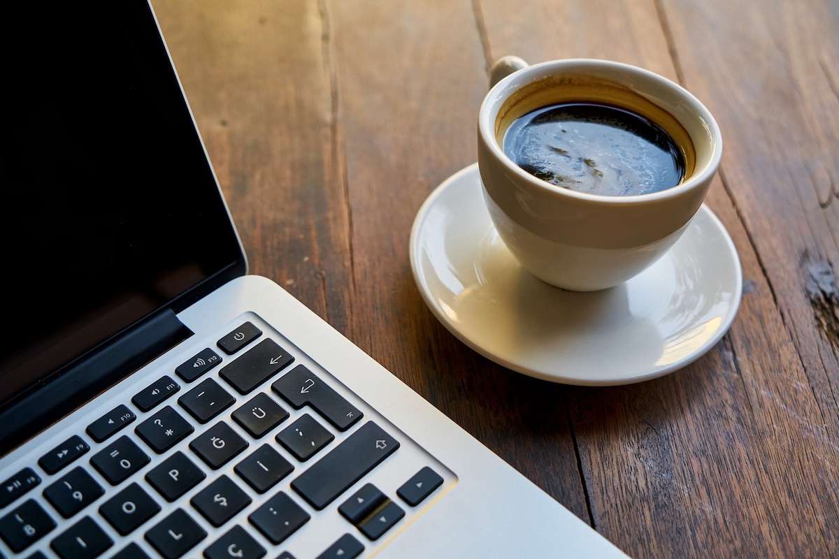Cup of coffee next to a laptop, representing caffeine as the most proven cognitive enhancer