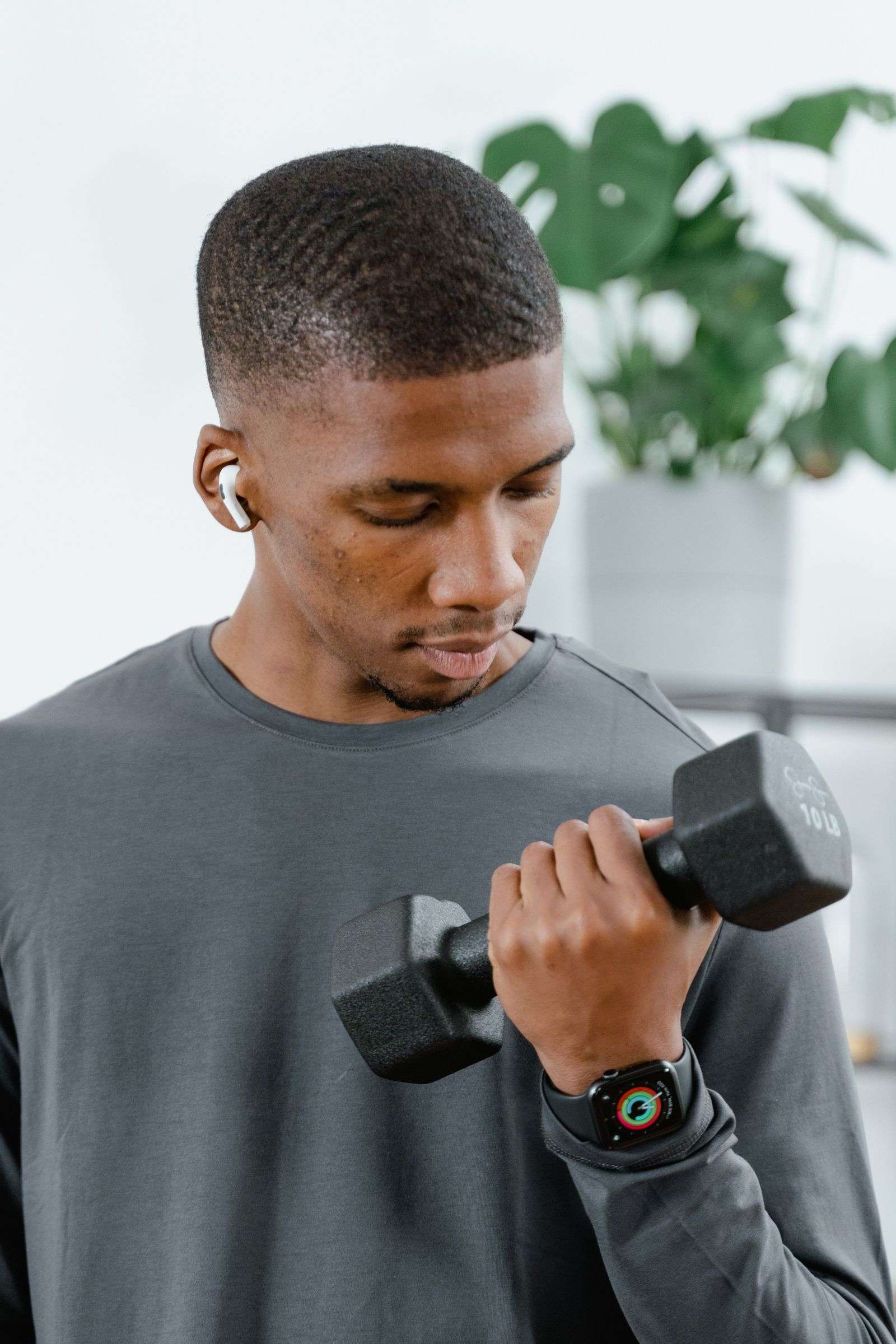 Home workout with dumbbells: man lifting weights indoors as part of strength training after 40