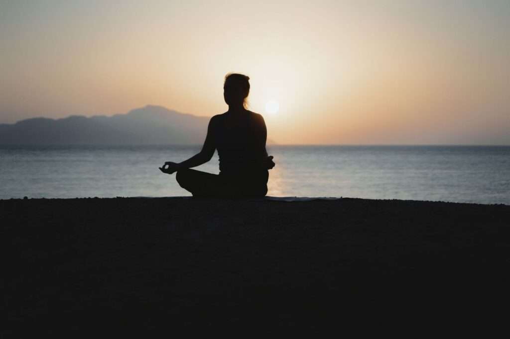 Person meditating at sunrise, a recovery practice the top biohackers use to manage stress