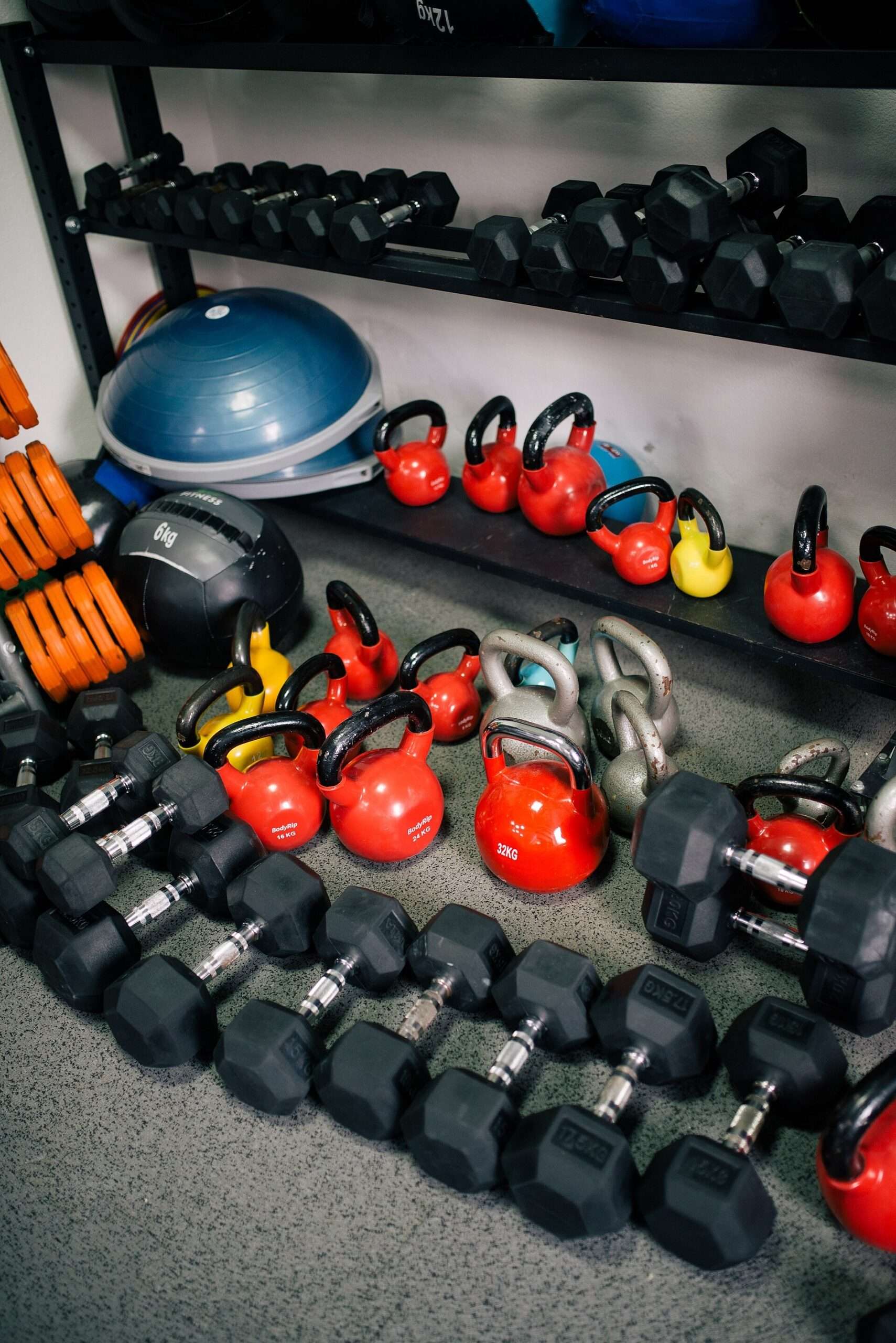 Colorful kettlebells and dumbbells arranged on racks in a gym